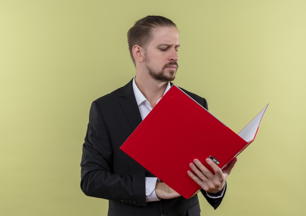 handsome-business-man-wearing-suit-holding-red-folder-looking-it-with-serious-face-standing-green-background.jpg мужчина
